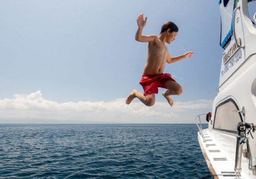 Kid jumping from the side of a boat